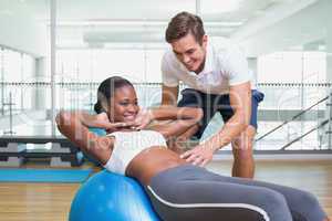 Personal trainer working with client on exercise ball