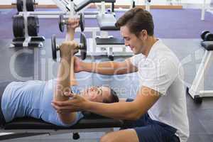 Personal trainer helping client lift dumbbells