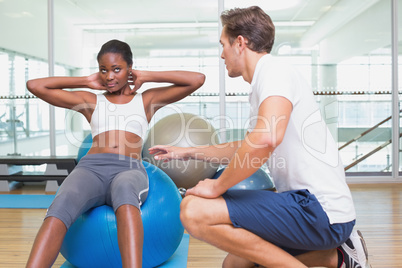 Personal trainer working with client on exercise ball