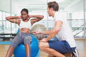 Personal trainer working with client on exercise ball