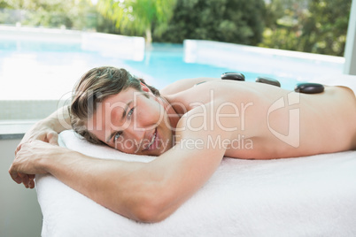 Handsome man receiving stone massage at spa center