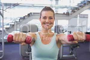 Fit brunette holding red dumbbells