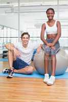 Personal trainer and client smiling at camera with exercise ball