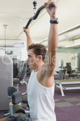 Fit man using the weights machine for his arms