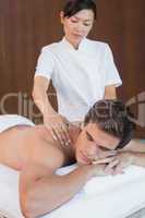 Man receiving shoulder massage at spa center