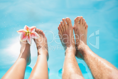 Couple feet against swimming pool on a sunny day