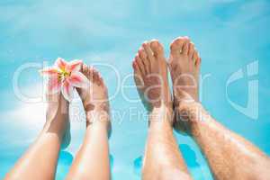 Couple feet against swimming pool on a sunny day