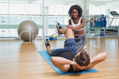 Personal trainer working with client on exercise mat