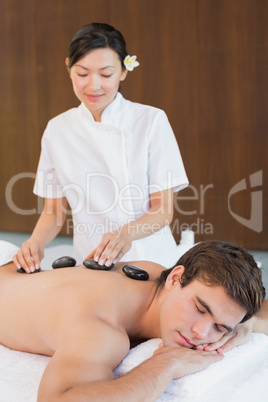 Young man receiving stone massage at spa center