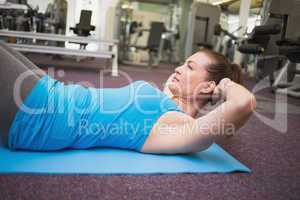 Fit brunette doing sit ups on exercise mat