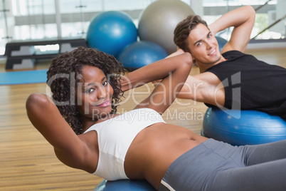 Couple doing sit ups on exercise balls