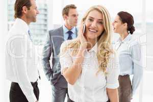 Businesswoman using mobile phone with colleagues behind