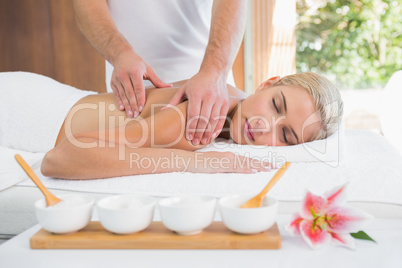 Woman receiving shoulder massage at spa center