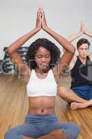 Fit couple sitting in lotus pose in fitness studio