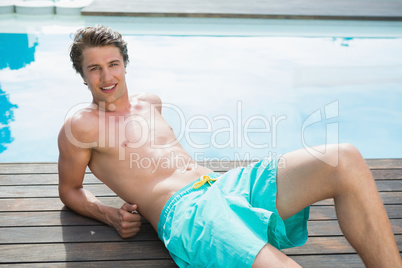 Portrait of a young man lying by swimming pool