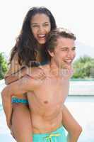 Man carrying cheerful woman by swimming pool