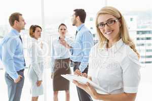 Businesswoman writing notes with colleagues behind