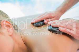 Mid section of woman receiving stone massage at health farm