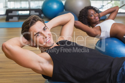 Couple doing sit ups on exercise balls