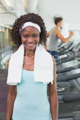 Pretty woman smiling at camera beside treadmills