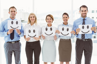 Business people holding happy smileys in office