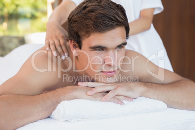 Man receiving shoulder massage at spa center