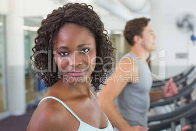 Fit woman smiling at camera on treadmill