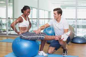 Personal trainer working with client on exercise ball