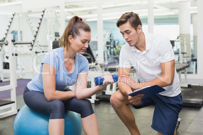 Personal trainer working with client holding dumbbell