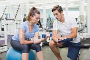 Personal trainer working with client holding dumbbell