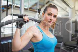 Fit brunette using weights machine for arms