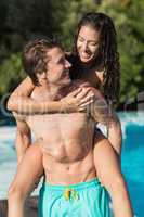 Man carrying cheerful woman by swimming pool