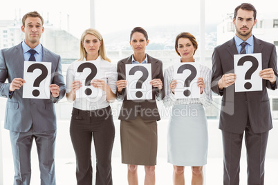 Business people holding question mark signs