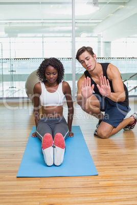 Personal trainer working with client on exercise mat