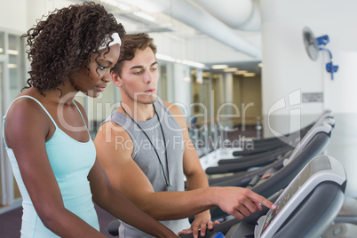 Fit woman on treadmill talking to personal trainer