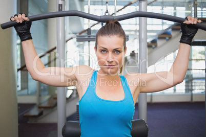 Fit brunette using weights machine for arms