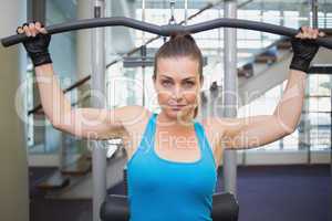 Fit brunette using weights machine for arms