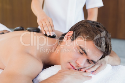 Young man receiving stone massage at spa center