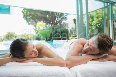 Couple lying on massage table at spa center