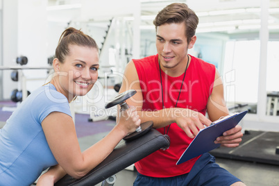 Personal trainer working with client holding dumbbell