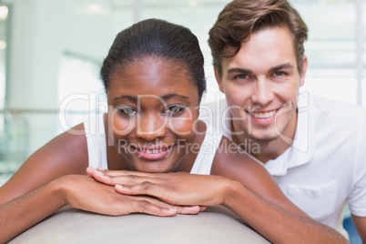 Personal trainer and client smiling at camera with exercise ball