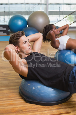 Couple doing sit ups on exercise balls