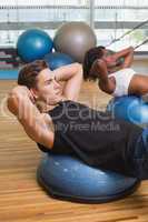 Couple doing sit ups on exercise balls