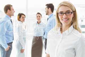 Businesswoman with colleagues behind at office