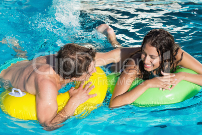 Couple in inflatable rings at swimming pool