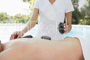 Mid section of man receiving stone massage at spa center