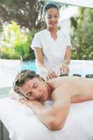 Handsome man receiving stone massage at spa center