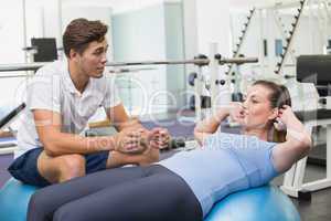 Personal trainer working with client on exercise ball