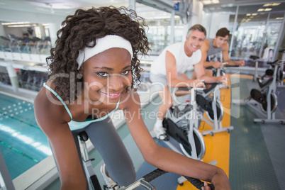 Three fit people working out on exercise bikes