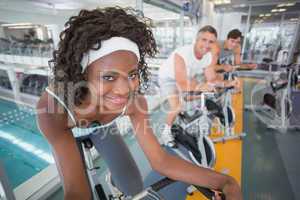 Three fit people working out on exercise bikes